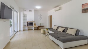 A modern living room with a grey sofa, a glass coffee table, and a dining area with a table and chairs. - Two bedroom cozy apartment in Banjole (Banjole)