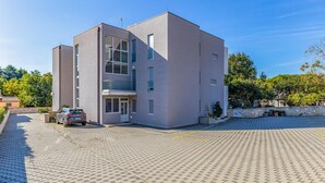 A modern building with a flat roof, large windows, and a paved entrance area. - Two bedroom cozy apartment in Banjole (Banjole)
