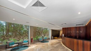 Eine moderne Lobby mit einer Rezeption, einer Sitzecke und großen Fenstern mit Blick auf eine natürliche Landschaft.