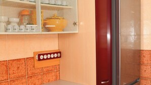 A kitchen with a refrigerator, wooden cabinets, a countertop, and a tiled backsplash. - Your cozy home in Agadir - discover comfort and tradition (Agadir)