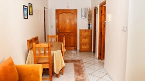 A dining area with a wooden table and chairs, a wooden cabinet, and a door with a phone on the wall. - Your cozy home in Agadir - discover comfort and tradition (Agadir)