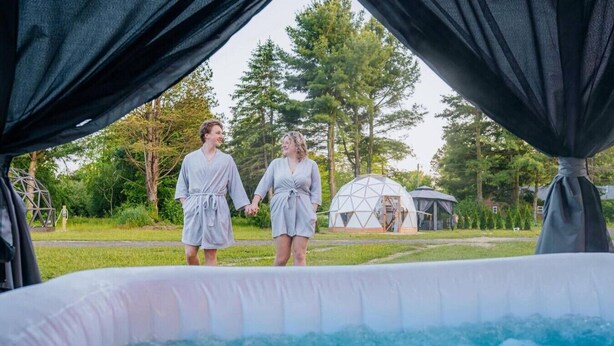 Two people holding hands in a garden with a hot tub and a geodesic dome structure. - Slate Serenity/Pet Friendly/Private Hot Tub (South Haven)