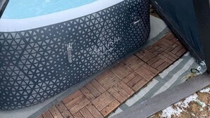 Un bain à remous extérieur à motifs géométriques, entouré d’une terrasse en briques et d’une plateforme en bois.