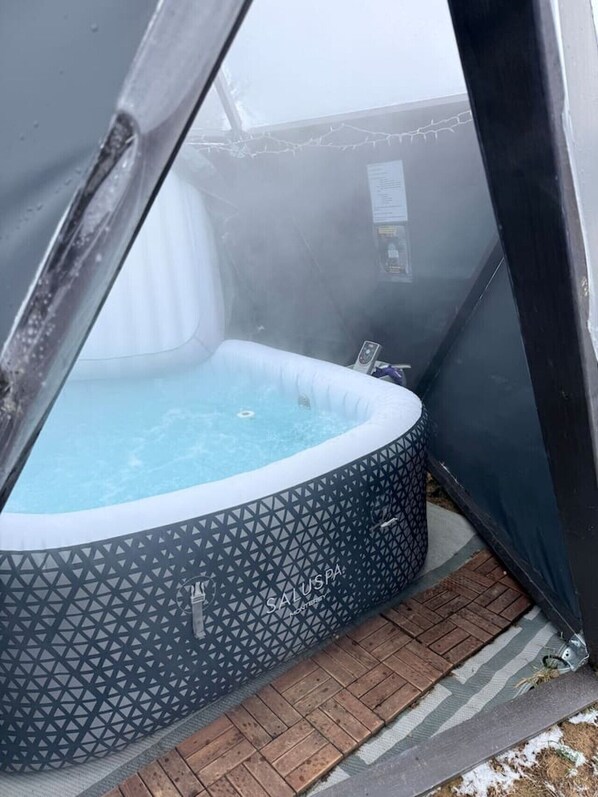 A hot tub with a geometric pattern, surrounded by a brick patio and a wooden deck. - Slate Serenity/Pet Friendly/Private Hot Tub (South Haven)