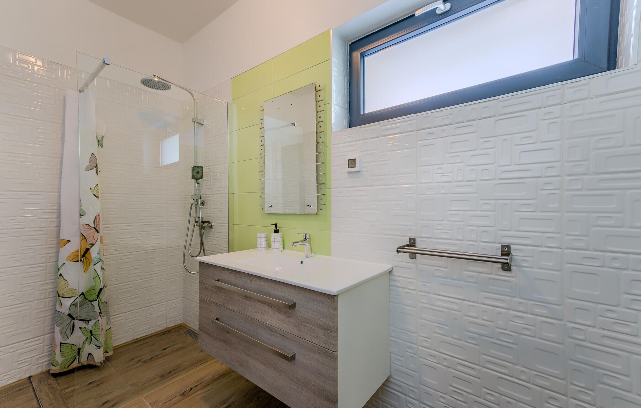 Une salle de bain avec une douche, un lavabo avec un miroir et une fenêtre.