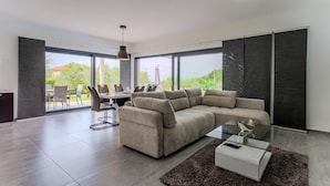 A modern living room with a sectional sofa, a glass coffee table, and a dining area with chairs and a table. - Pet friendly home in Novigrad (Novigrad)