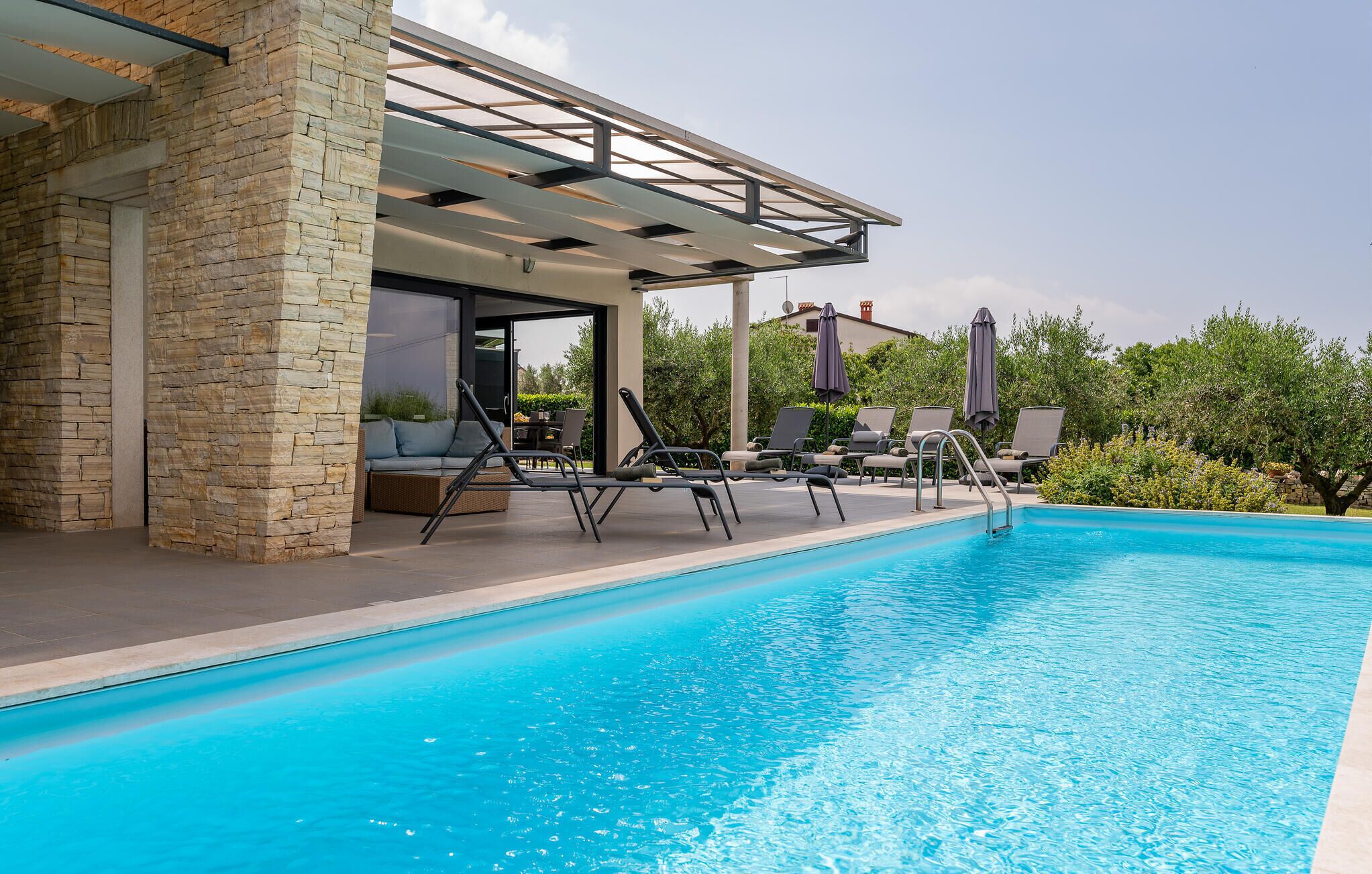 A swimming pool with lounge chairs and a covered seating area.