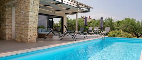 A swimming pool with lounge chairs and a covered seating area.