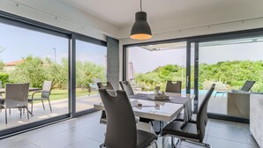 A modern dining area with a glass table and chairs, large windows, and a view of the outdoors. - Pet friendly home in Novigrad (Novigrad)