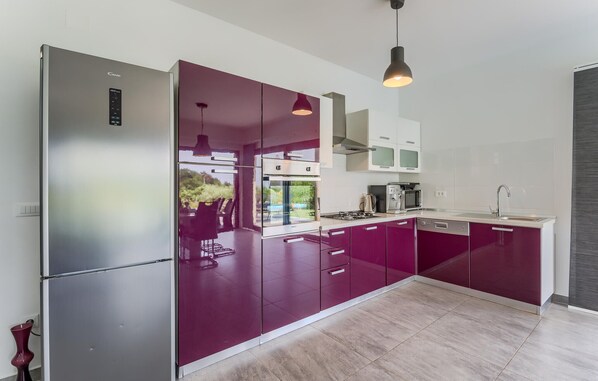 A modern kitchen with a stainless steel refrigerator, a gas stove, and a microwave.