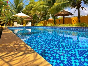A swimming pool with a checkered tile pattern, surrounded by palm trees and lounge chairs. - Pousada Costeira da Barra (Maragogi)