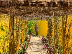 A pathway flanked by yellow walls and greenery, leading to a central area with a yellow background. - Pousada Costeira da Barra (Maragogi)