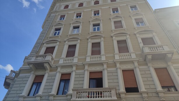 A multi-story building with classical architecture, featuring columns, decorative moldings, and large windows with shutters. - Colori di Trieste - TriesteCenter (Trieste)
