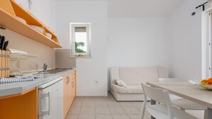 Een kleine keuken met een eethoek, met een ingebouwde oven, een spoelbak en een raam dat voor natuurlijk licht zorgt.