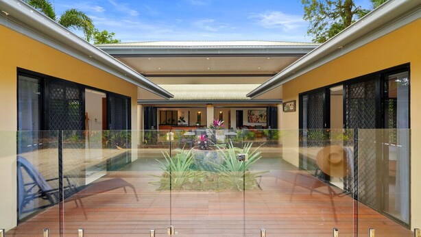 A modern house with a covered patio, glass railings, and a central garden area. - The Pavilion at Trinity Beach (Trinity Beach)