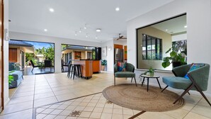 A spacious living area with a kitchen, a bar area, and a seating area with two armchairs and a coffee table. - The Pavilion at Trinity Beach (Trinity Beach)