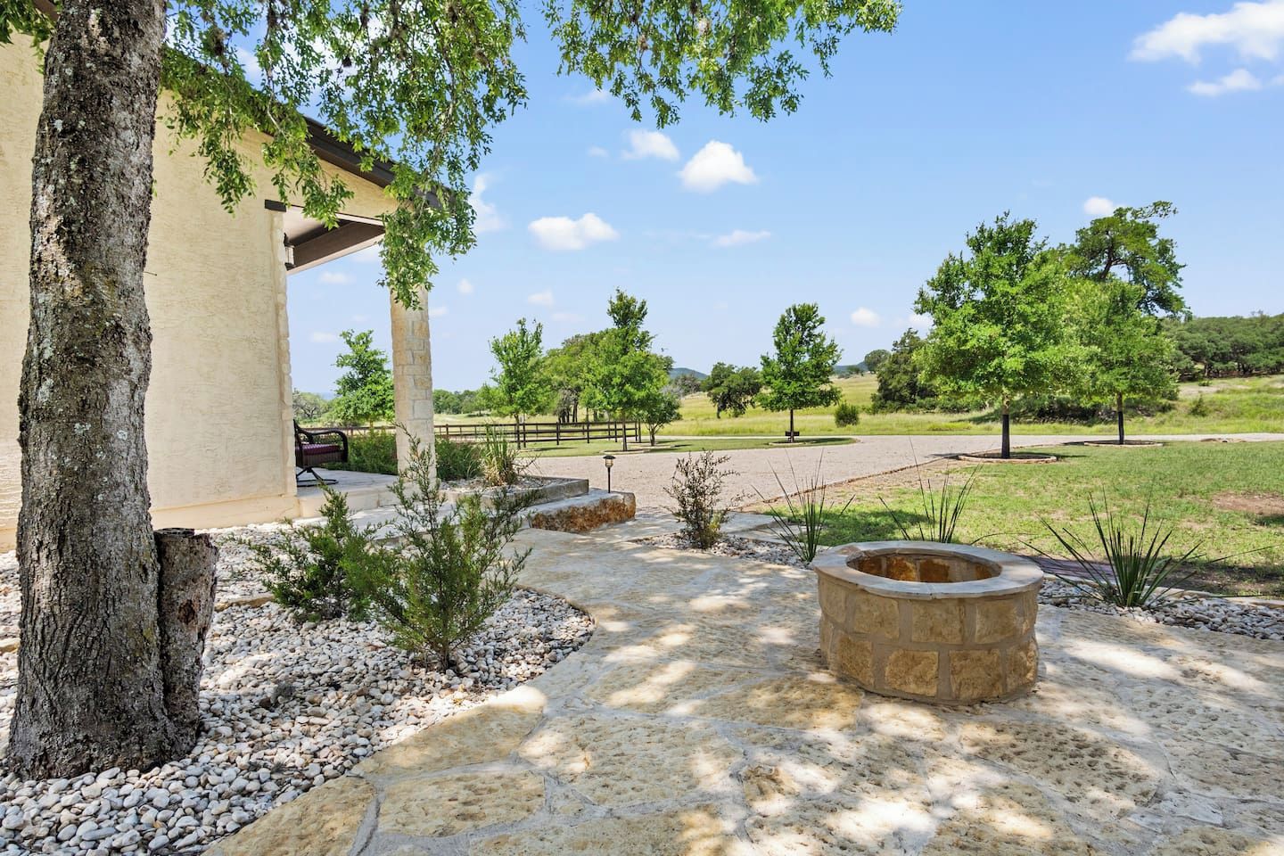A patio area with a pergola, stone pathway, and a fire pit.