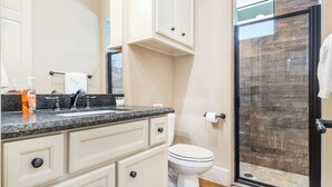 A bathroom with a granite countertop, a white toilet, and a glass shower enclosure. - Timbuctoo 1 | Ranch Stay w/ Wildlife Views (Bandera)