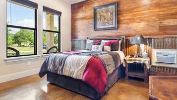 A bedroom with a large bed, a nightstand, a lamp, and a framed picture on the wall.