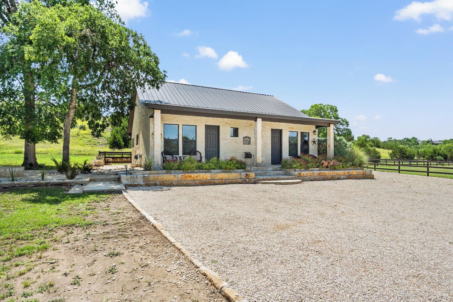 A two-story building with a gravel driveway and a fenced area.