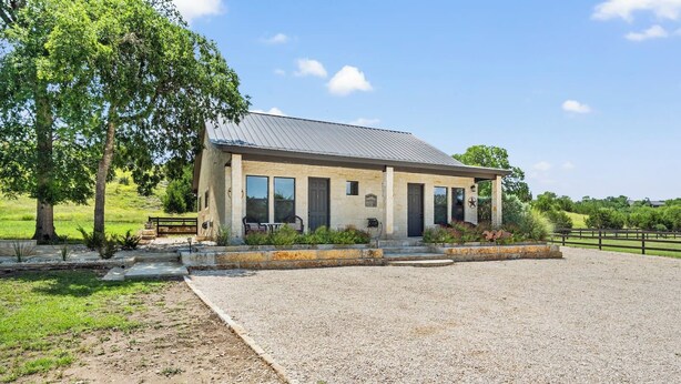 A two-story building with a gravel driveway and a fenced area. - Timbuctoo 1 | Ranch Stay w/ Wildlife Views (Bandera)