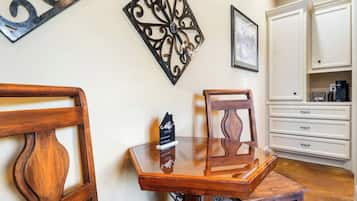 A dining area with a wooden table and chairs, a decorative wall piece, and a white cabinet with drawers.
