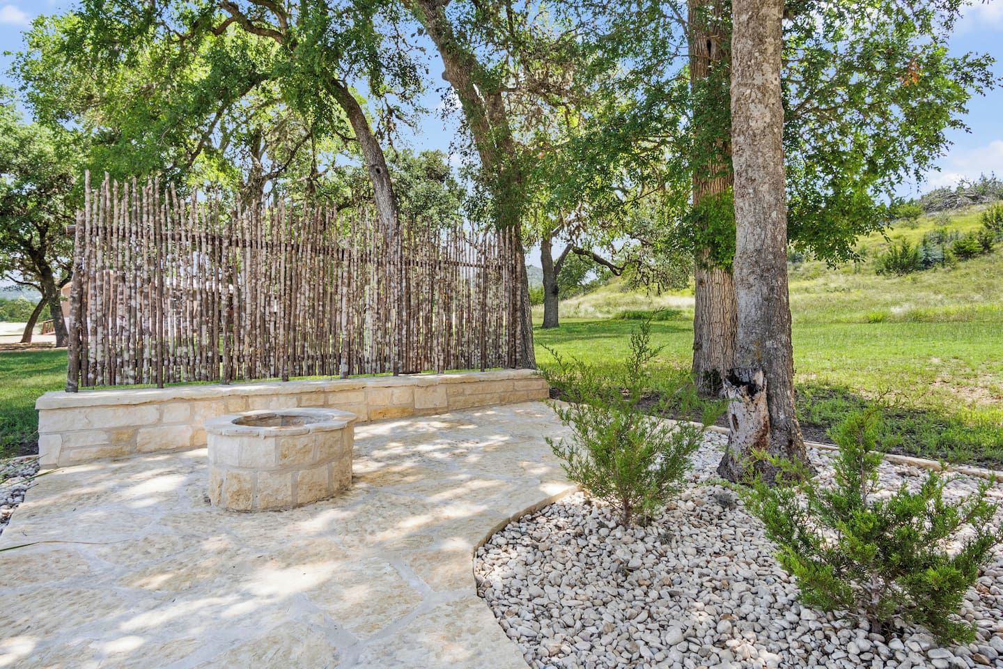 An outdoor patio area with stone flooring, a stone bench, and a small fire pit.