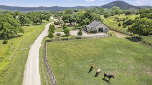Una propiedad rural con un pastizal cercado, una casa y un camino de tierra.
