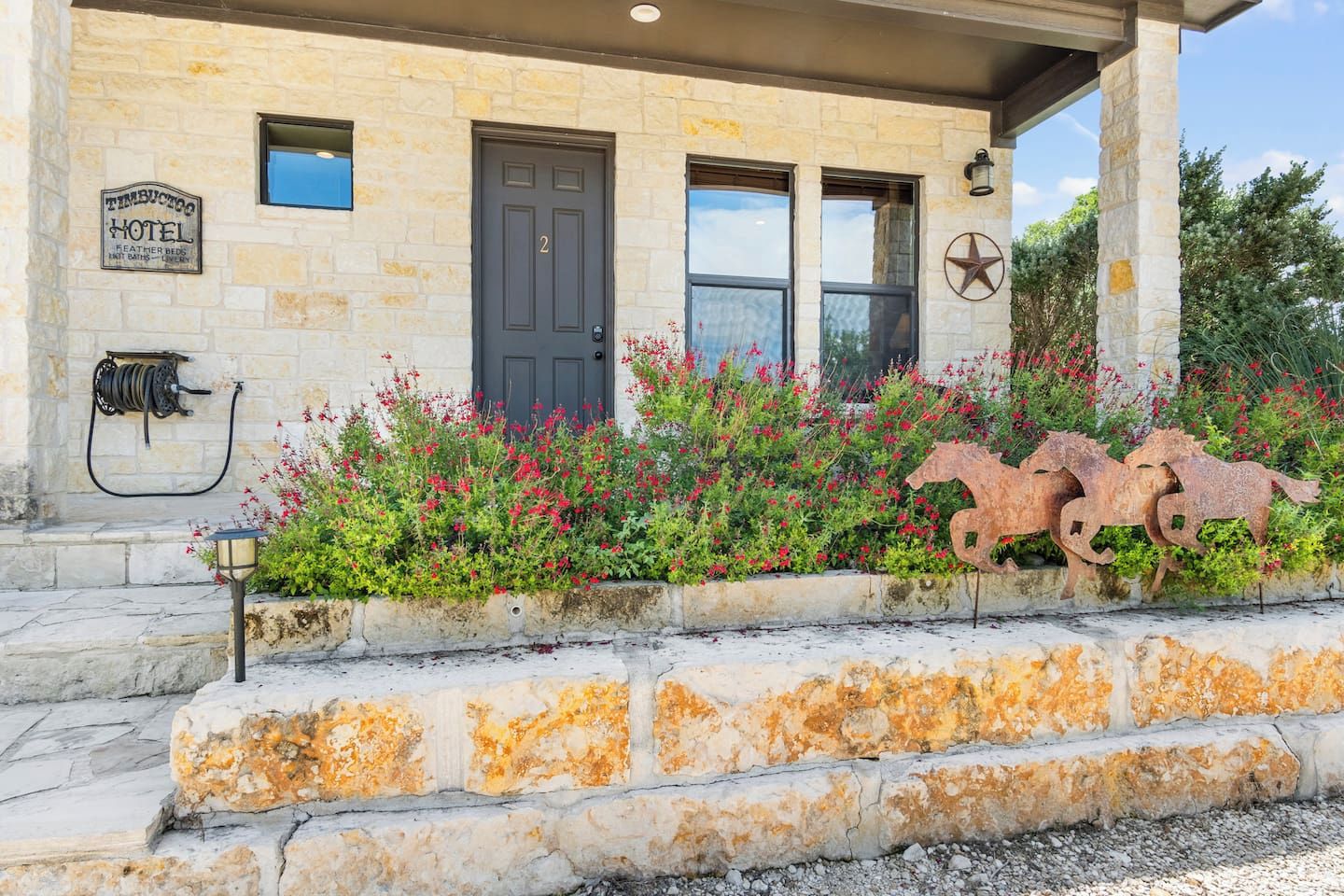 A stone building with a dark door, a sign indicating a hotel, and a decorative metal horse sculpture.