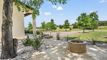 Un patio con una pérgola, un sendero de piedra y un hogar para la chimenea.