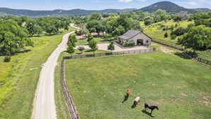A fenced property with a dirt road, a barn, and a grassy field. - Timbuctoo 2 | Cozy Ranch Suite Near Cowboy Capital (Bandera)