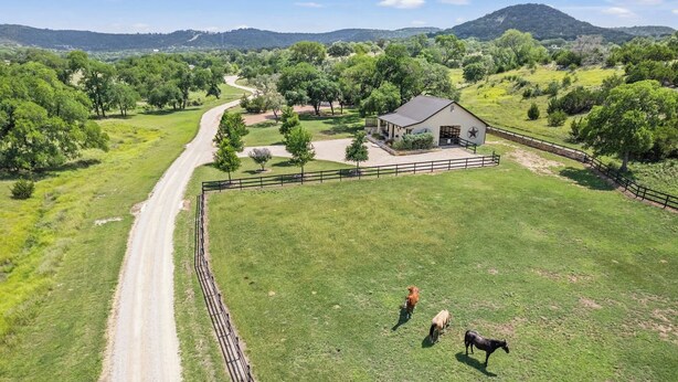 A fenced property with a dirt road, a barn, and a grassy field. - Timbuctoo 2 | Cozy Ranch Suite Near Cowboy Capital (Bandera)