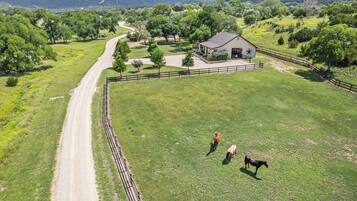 A fenced property with a dirt road, a barn, and a grassy field.