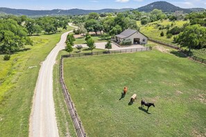 A fenced property with a dirt road, a barn, and a grassy field. - Timbuctoo 2 | Cozy Ranch Suite Near Cowboy Capital (Bandera)
