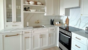 Een moderne keuken met witte kasten, een zwarte kookplaat en een marmeren spatwand.