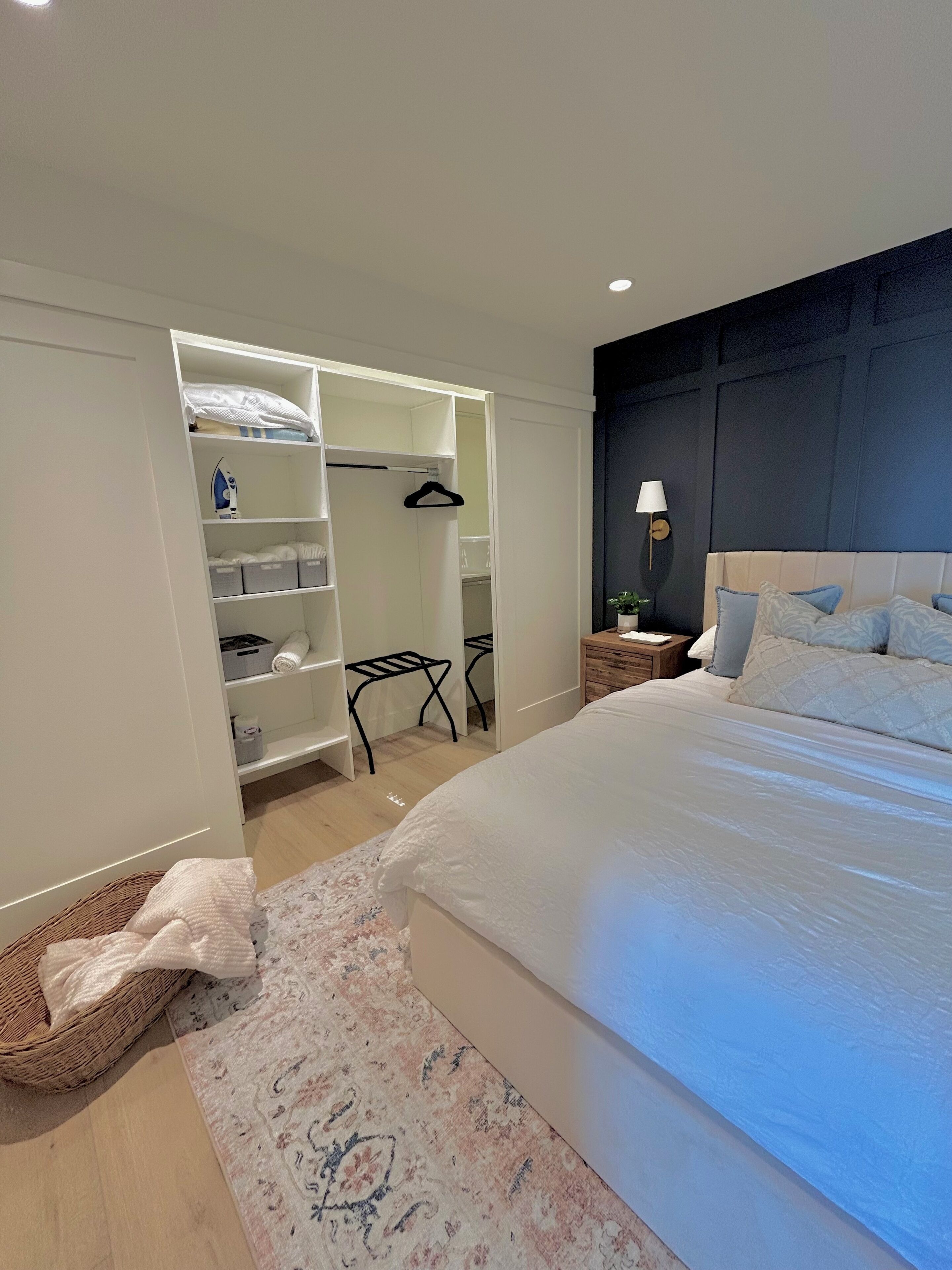 Un dormitorio con una cama grande, un vestidor y una mesita de noche con lámpara.