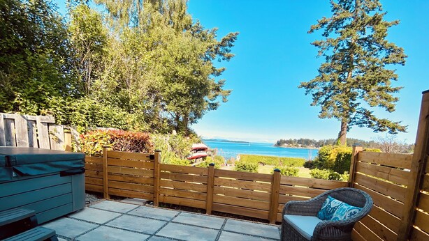 Een terras met uitzicht op de oceaan, een houten hek en tuinmeubilair.