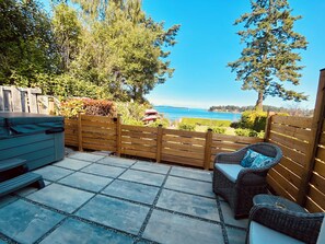 A patio with a view of the ocean, a wooden fence, and outdoor furniture.