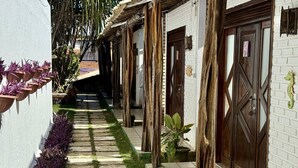 A narrow pathway with stone tiles and grass, flanked by white brick walls and wooden pillars. - Oceana Suites Villas de Tibau (Tibau do Sul)