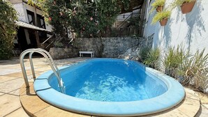 A small, round swimming pool with a metal ladder, surrounded by stone tiles and potted plants. - Oceana Suites Villas de Tibau (Tibau do Sul)
