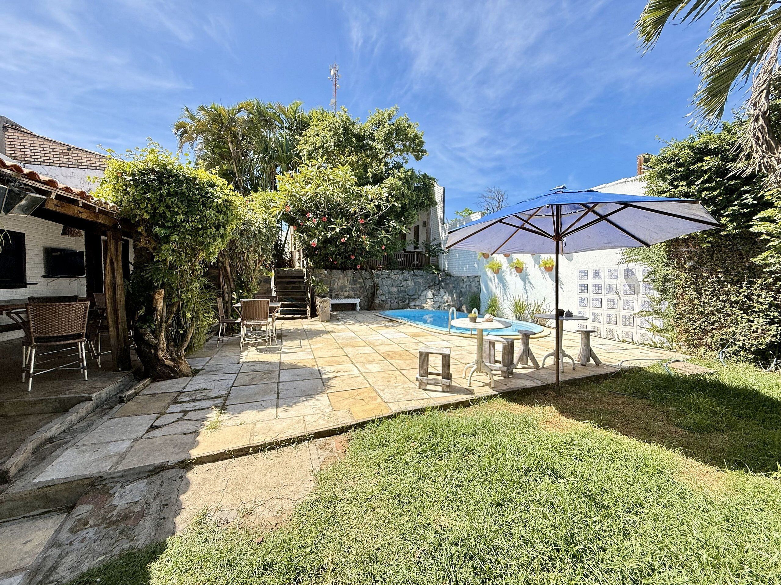 Un jardin avec une piscine, du mobilier d’extérieur et une pergola.