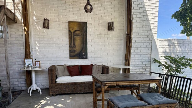 A cozy outdoor seating area with a wicker sofa, a wooden table, and a cushioned bench. - Oceana Suites Villas de Tibau (Tibau do Sul)