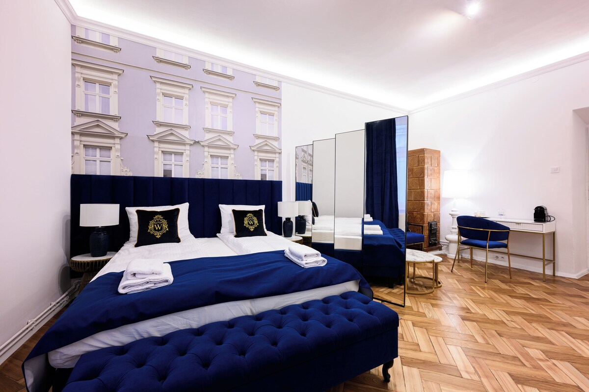 A hotel room with a large bed, a desk, and a mirror.