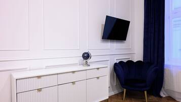 A modern room with a white cabinet, a globe, a dark blue chair, and a mounted TV.