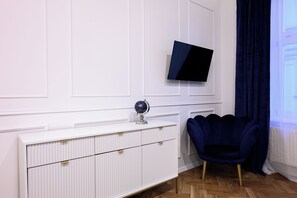 Ein moderner Raum mit einem weißen Schrank, einem Globus, einem dunkelblauen Sessel und einem an der Wand befestigten Fernseher.