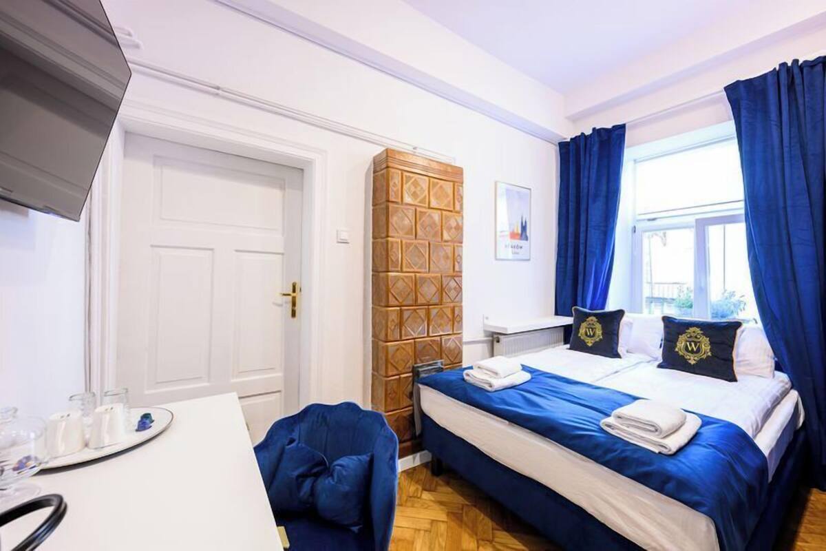 A hotel room with a bed, a desk, a chair, and a window with curtains.