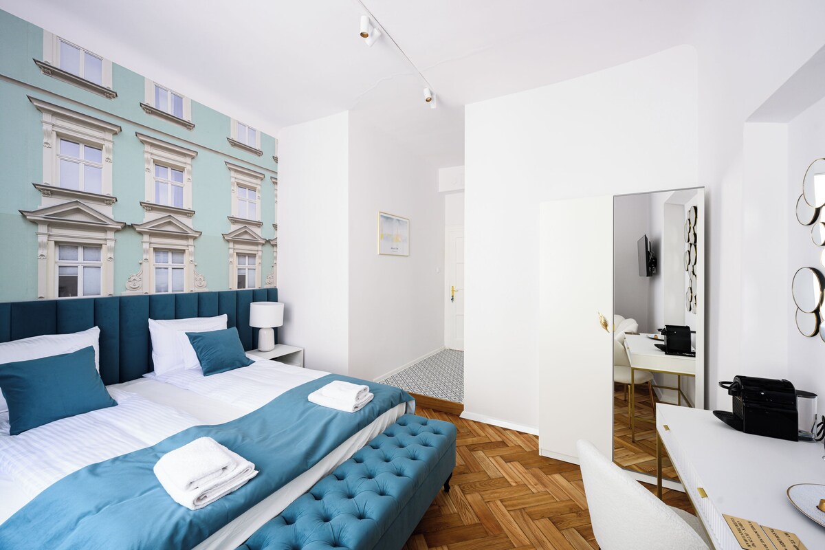 A modern hotel room with a large bed, a desk, and a mirror.
