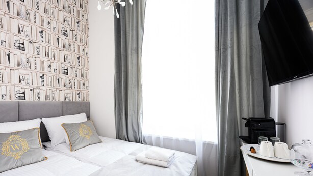 A hotel room with a neatly made bed, a wall-mounted TV, and a breakfast tray with coffee and tea. - Wiślna Main Square Apartments Self Check-in (Kraków)