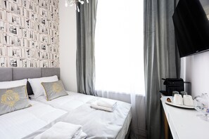 A hotel room with a neatly made bed, a wall-mounted TV, and a breakfast tray with coffee and tea. - Wiślna Main Square Apartments Self Check-in (Kraków)