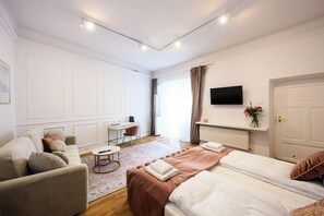 A modern hotel room with a bed, a sofa, a desk, and a TV. - Wiślna Main Square Apartments Self Check-in (Kraków)